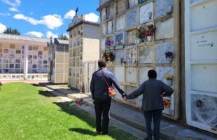 Pareja de visitantes rinde homenaje en una tumba en el Cementerio del Sur.